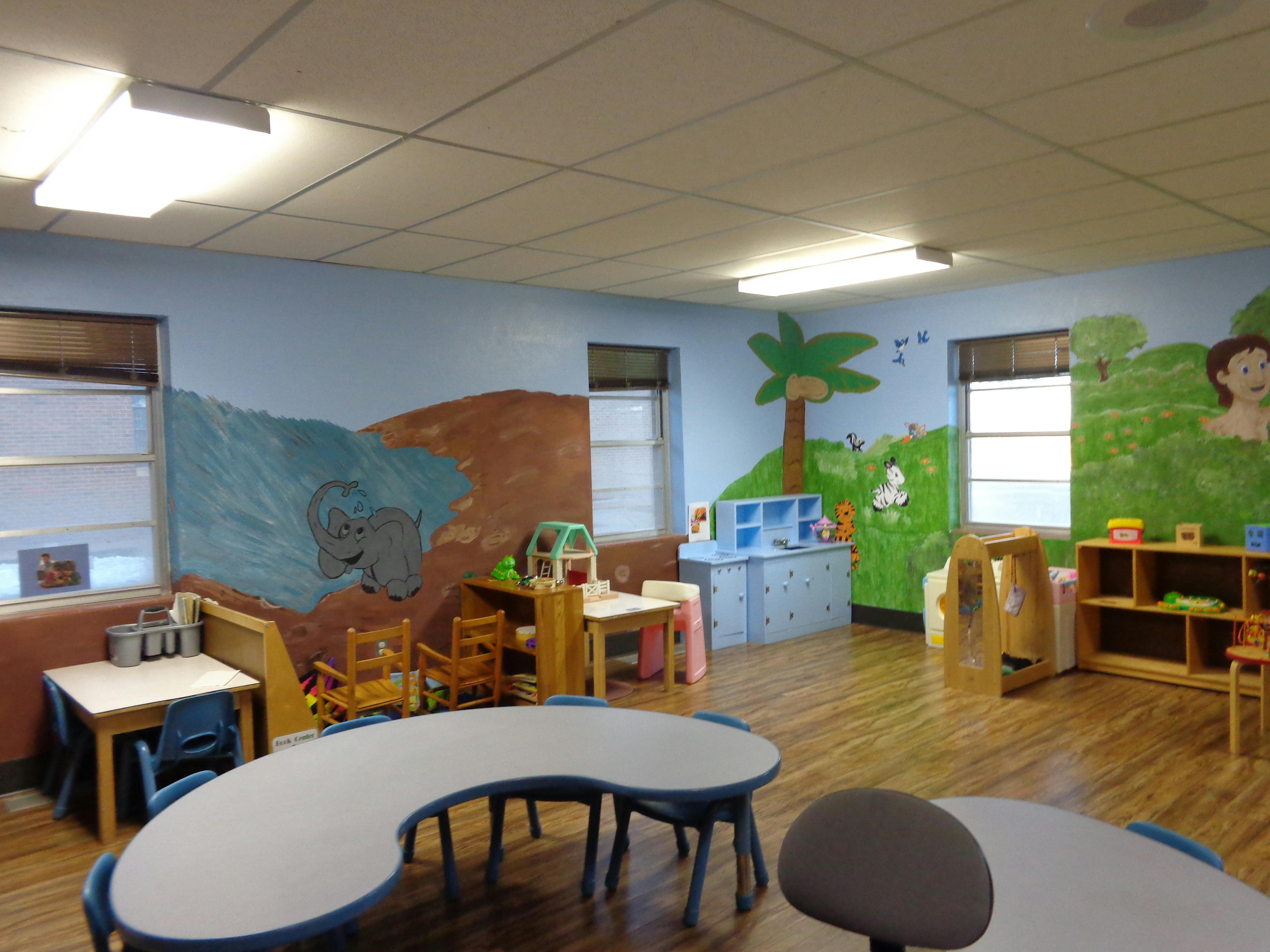 Classroom with tables, chairs, and murals on the walls