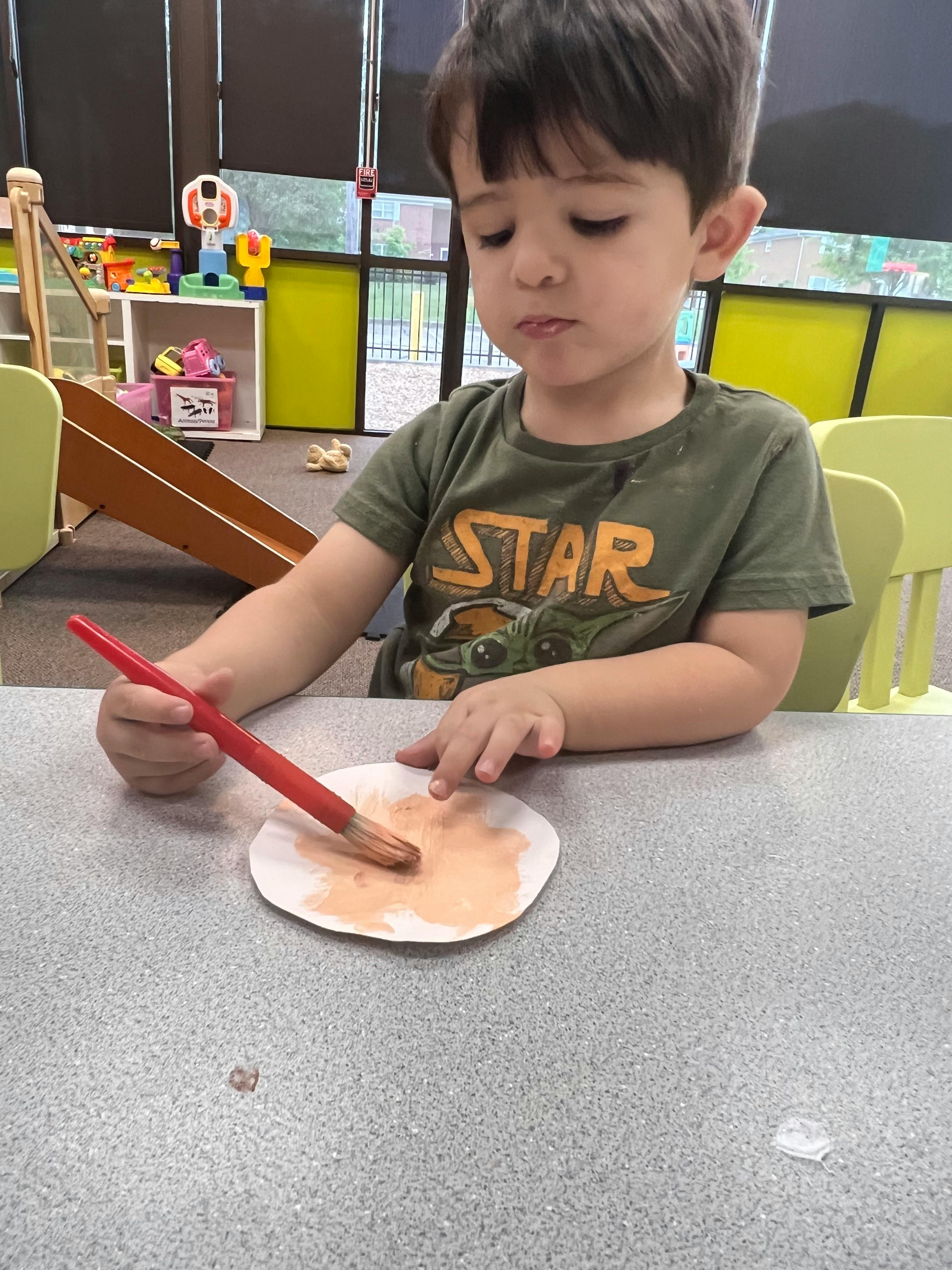 Child painting a paper plate with a brush