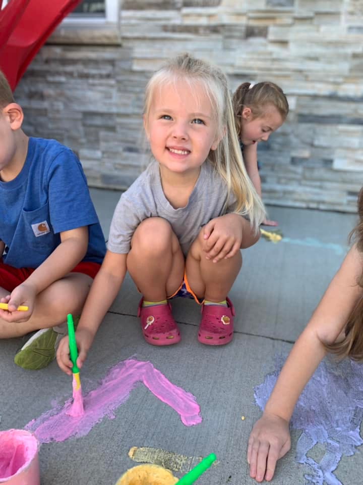 Child painting with chalk on the ground