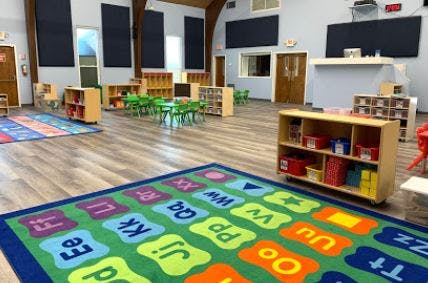 Classroom with alphabet rug, small tables and chairs, and storage shelves