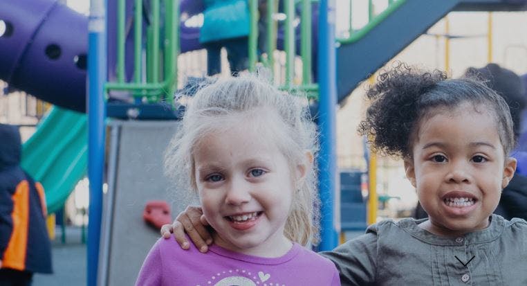 Two children smiling in a playground