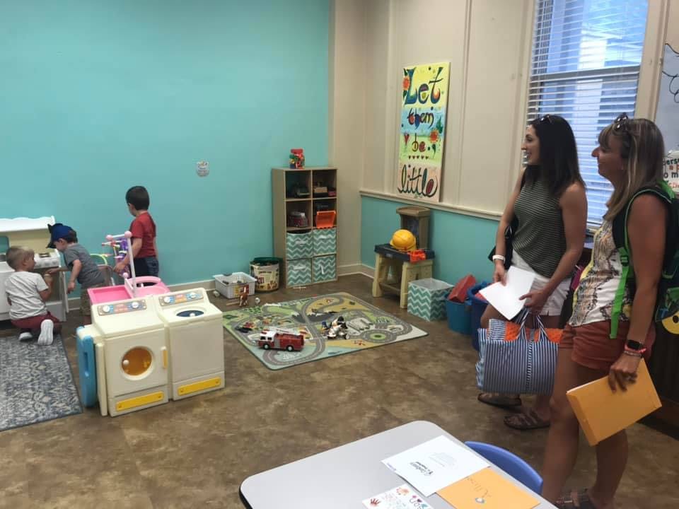 Two people observing children playing in a classroom