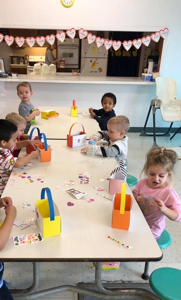 Children sitting at a table doing crafts with craft supplies