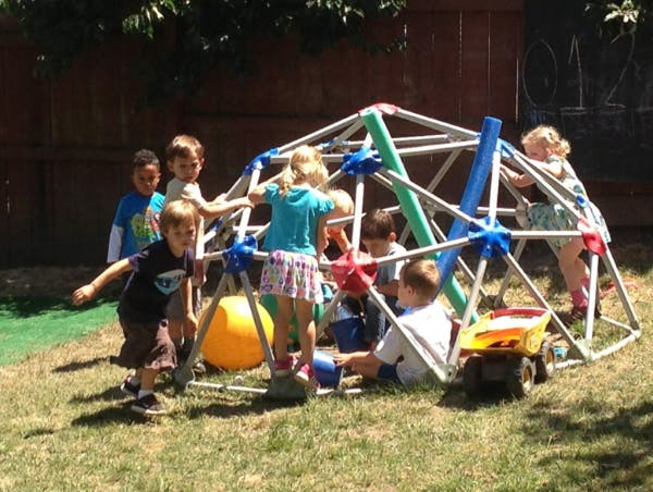 Children playing on a geodesic dome climber in a yard