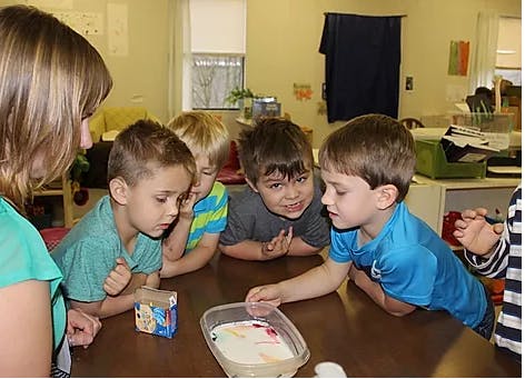 Adult and children looking at a container on a table
