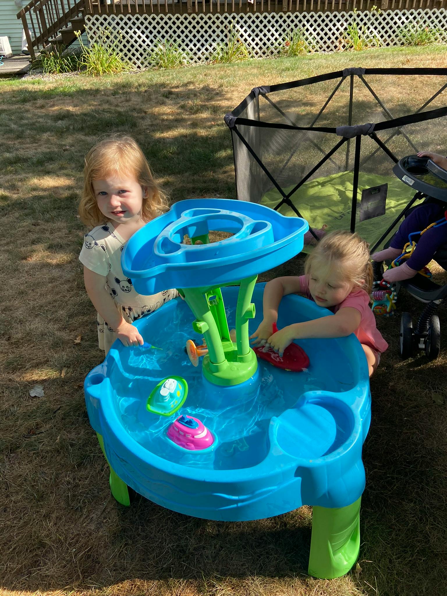 Two children playing with a water table outdoors