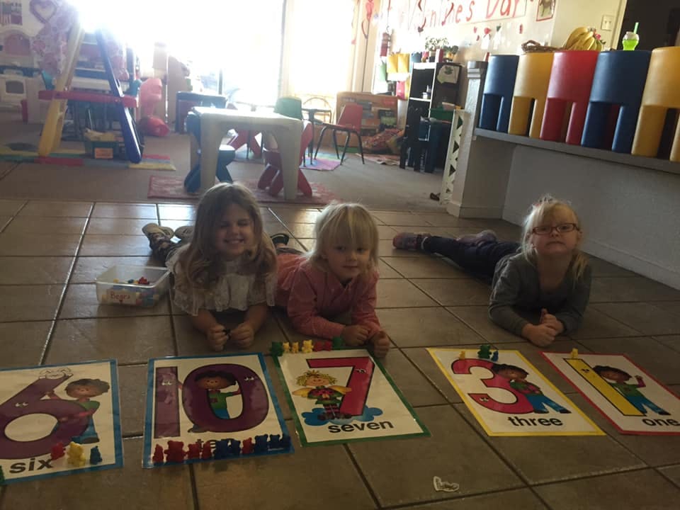 Three children lying on the floor with number cards