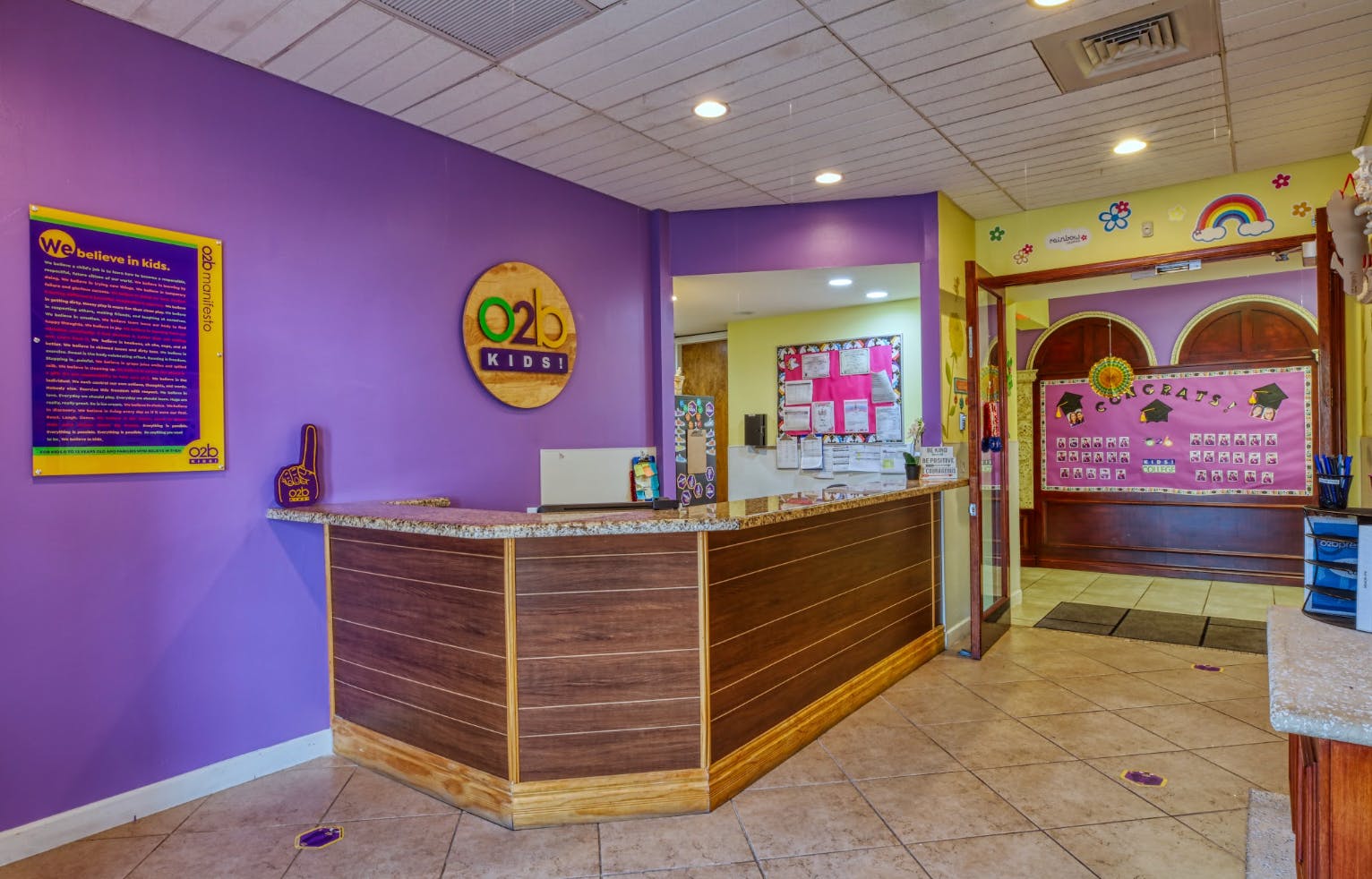 Reception desk with “O2b Kids!” sign, purple and yellow walls