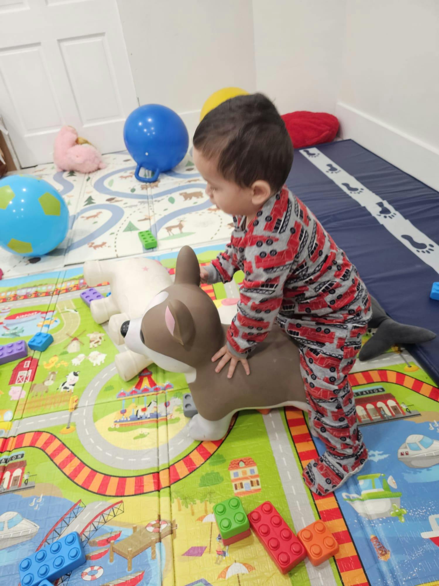 Child standing on a toy deer on a playmat