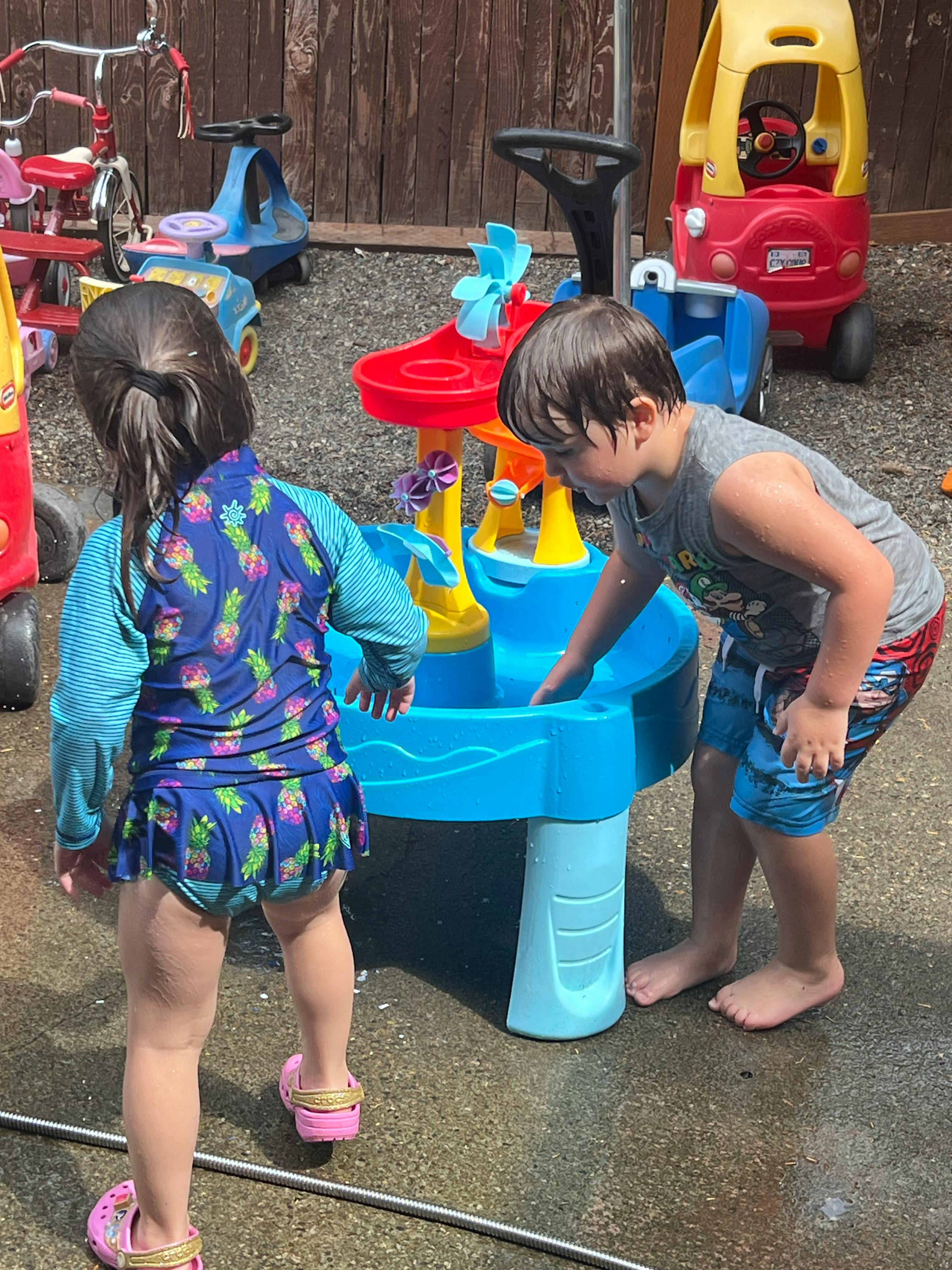 Two children playing with a water table outdoors