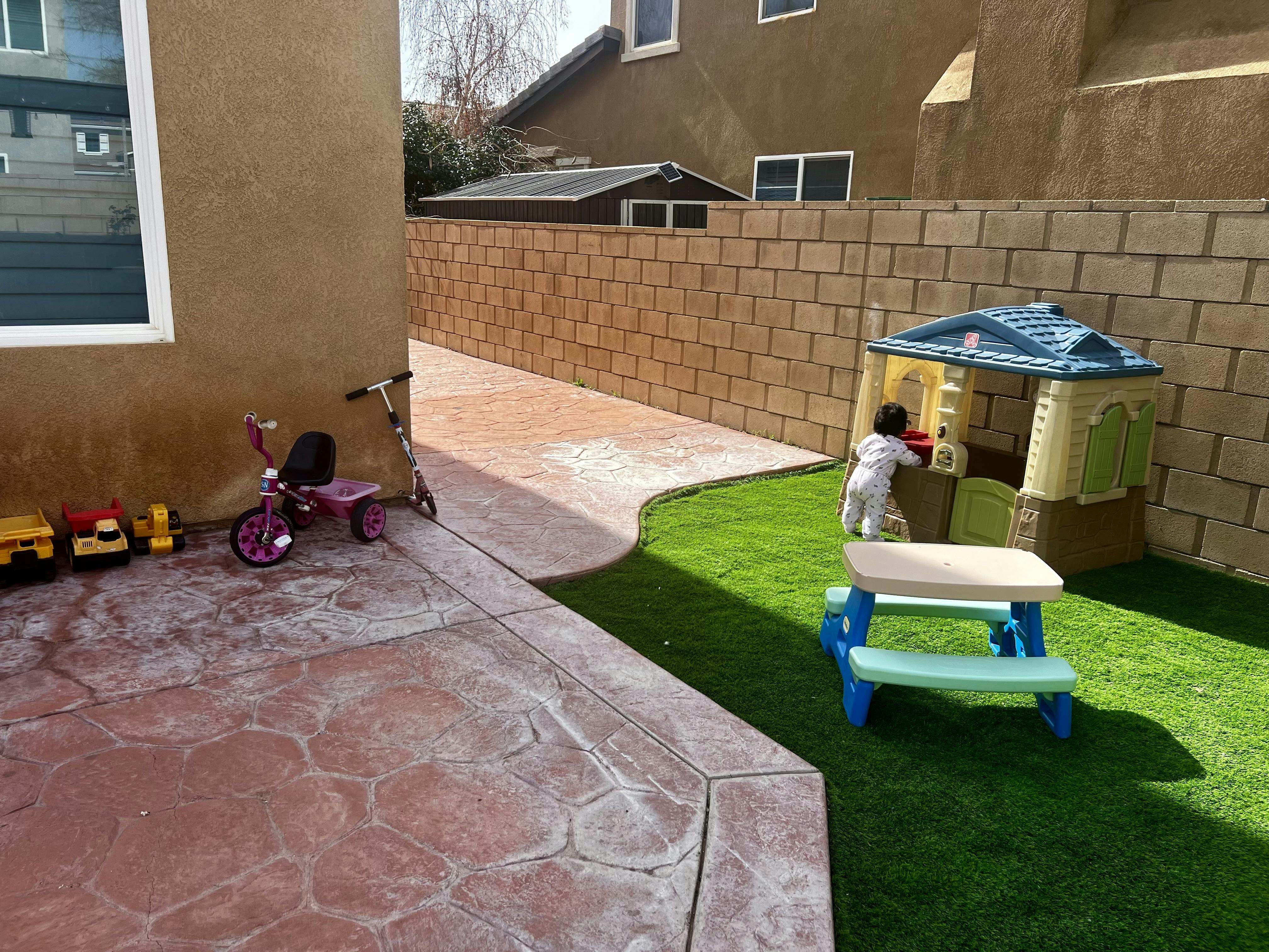 Child playing in an outdoor playhouse on artificial grass