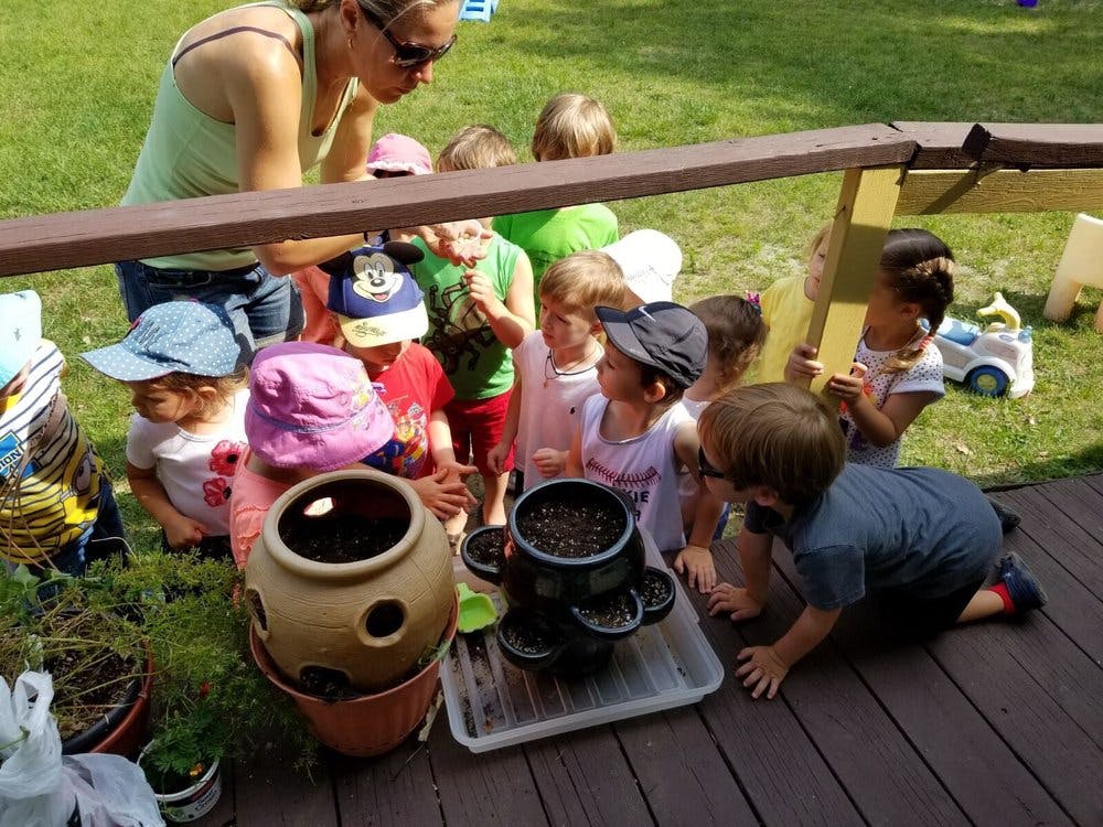 Adult and children gathered around potted plants on a deck