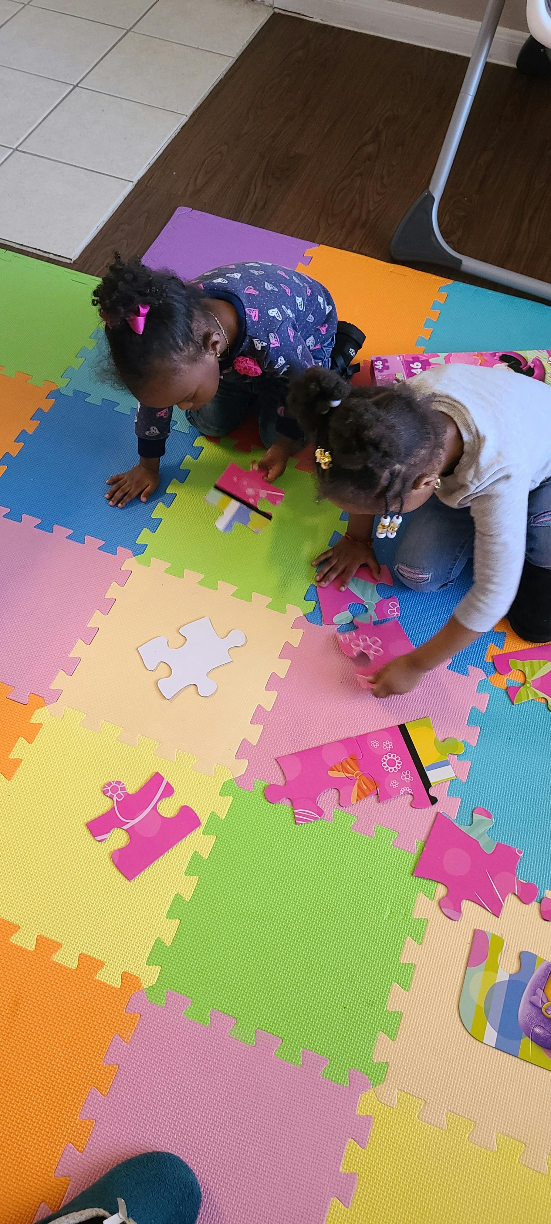 Two children on a colorful playmat, assembling a puzzle
