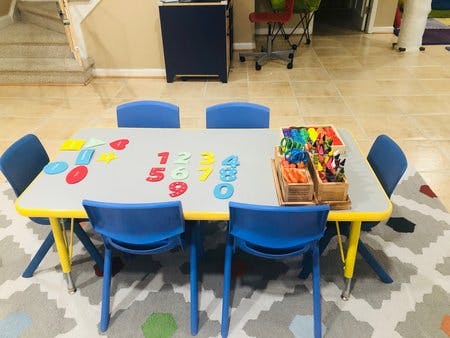 Table with colorful numbers, shapes, and art supplies in a classroom