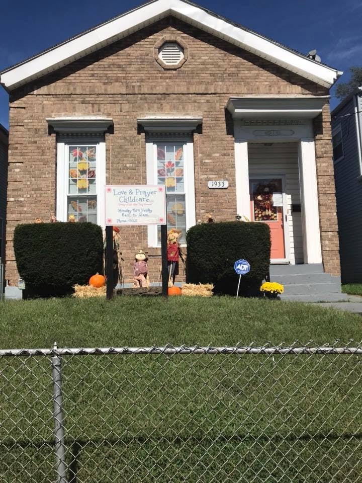 Brick house with a sign for "Love & Laughter Childcare" and fall decorations
