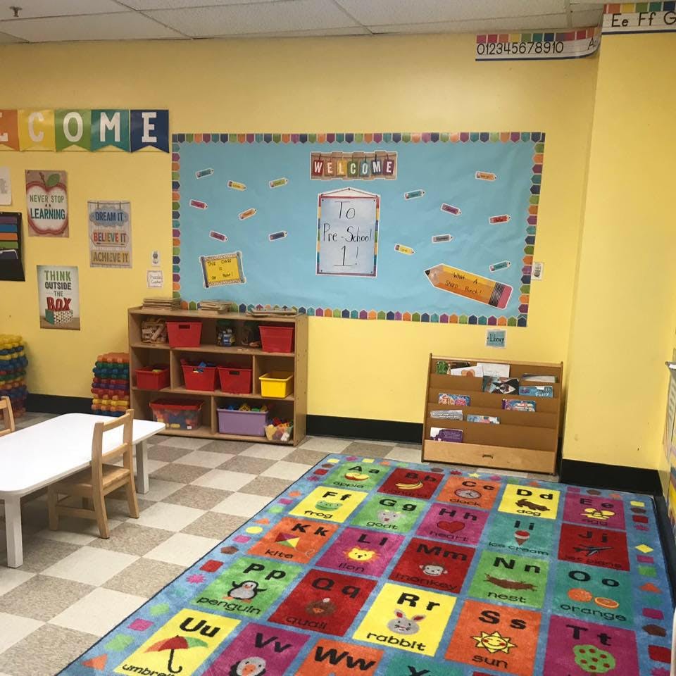 Classroom with an alphabet rug, shelves, and a bulletin board