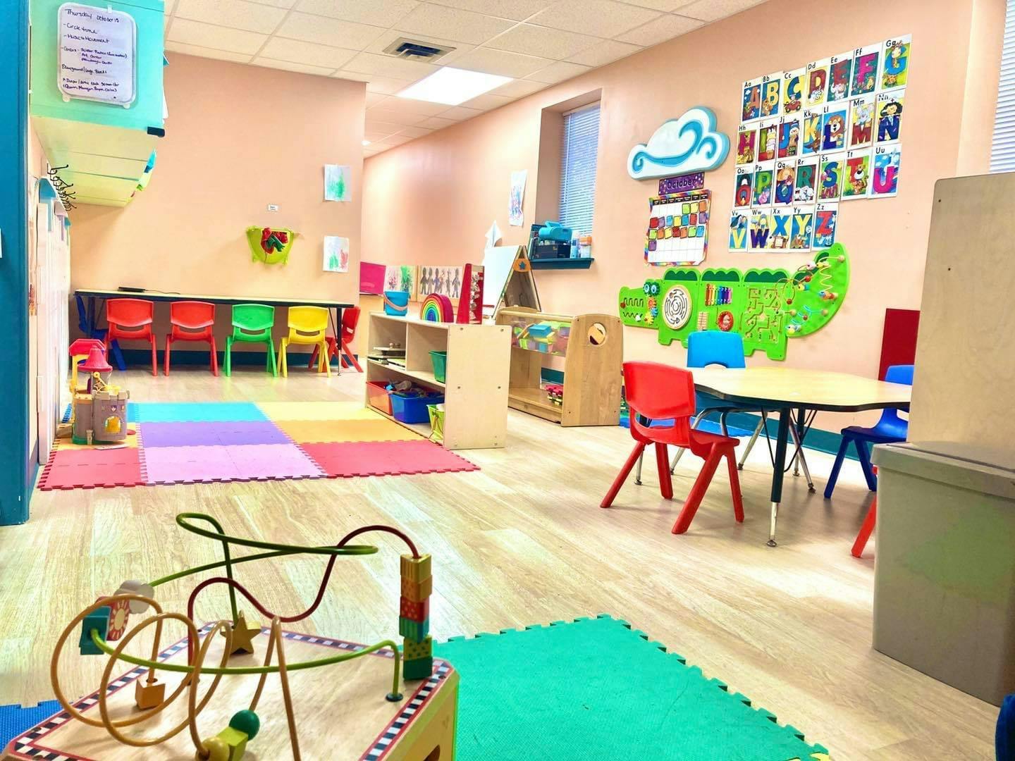 Playroom with colorful mats, small tables and chairs, and educational decorations