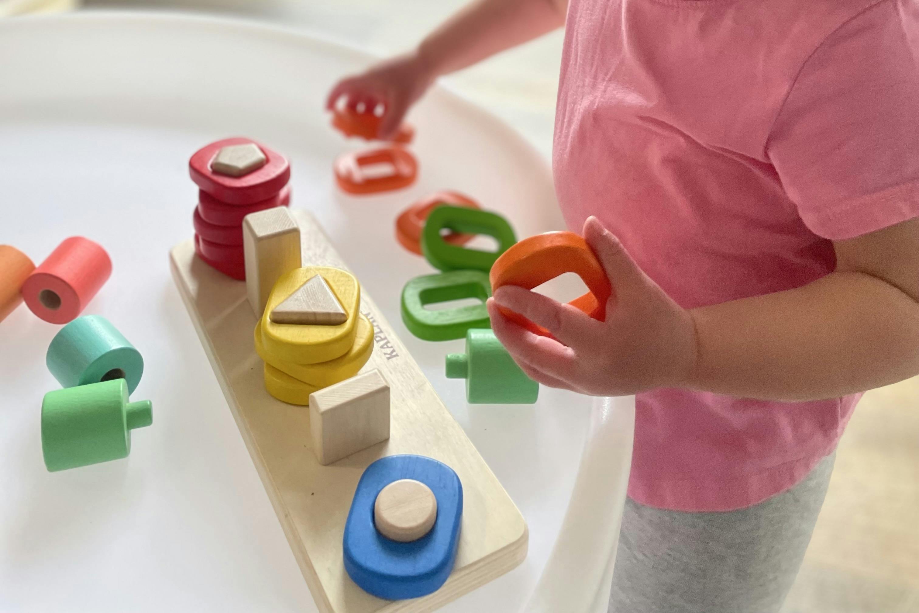 Child playing with colorful wooden shape sorter toy