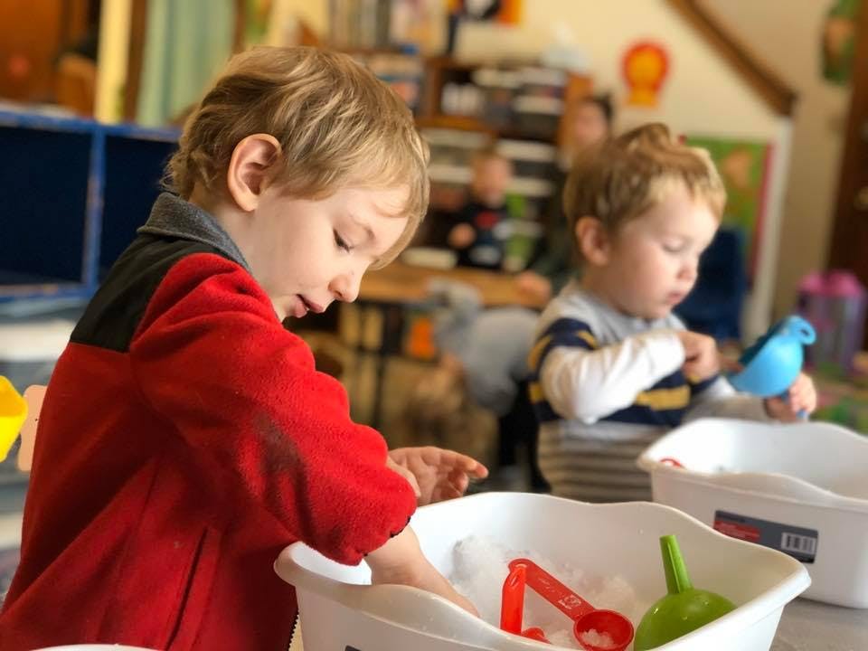 Two children playing with sensory bins in a classroom