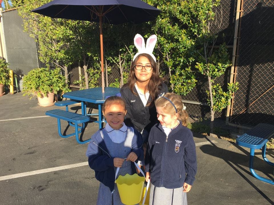 Person wearing bunny ears with two children holding buckets