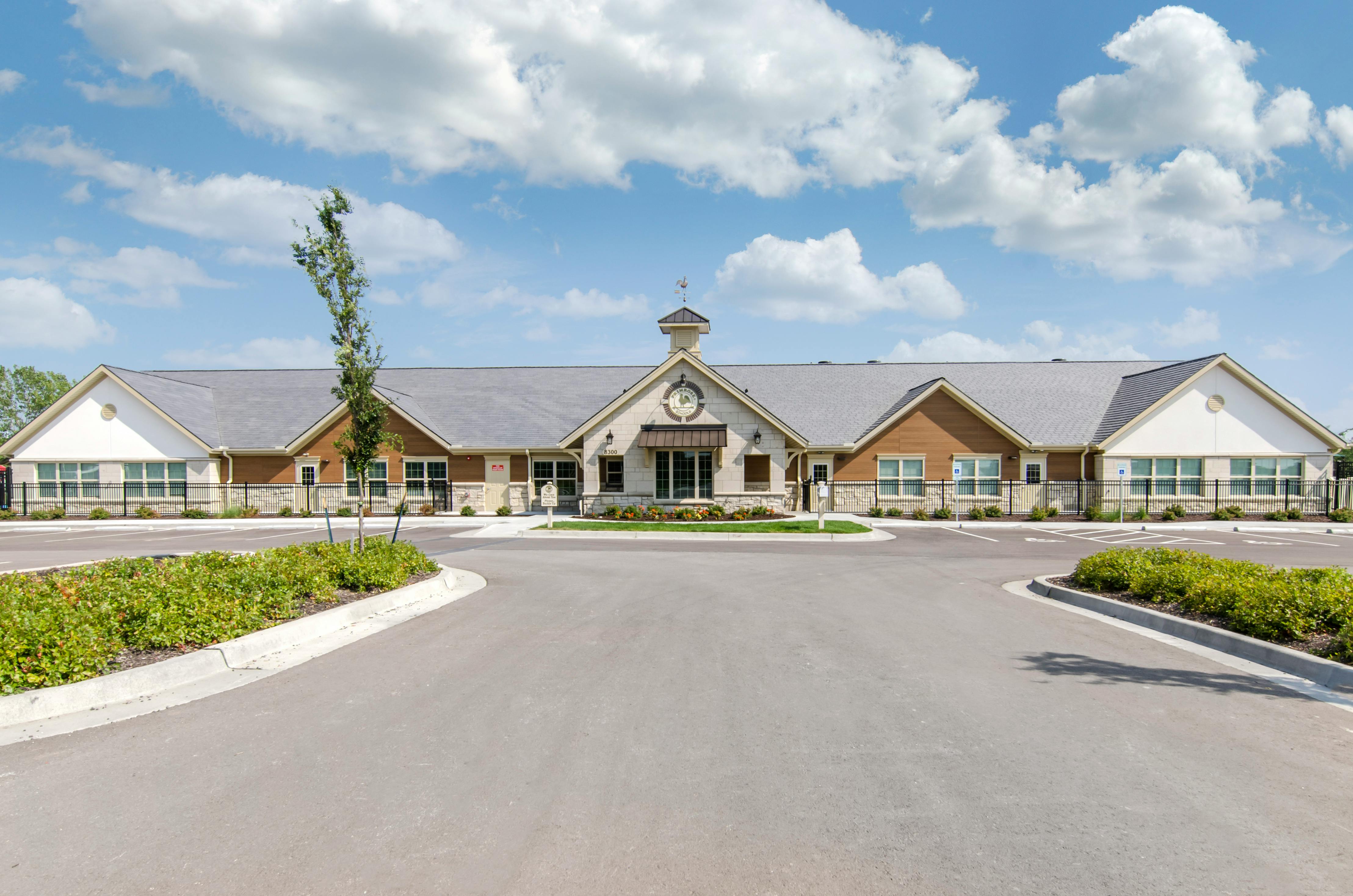 A long, single-story building with a central cupola and a paved parking area