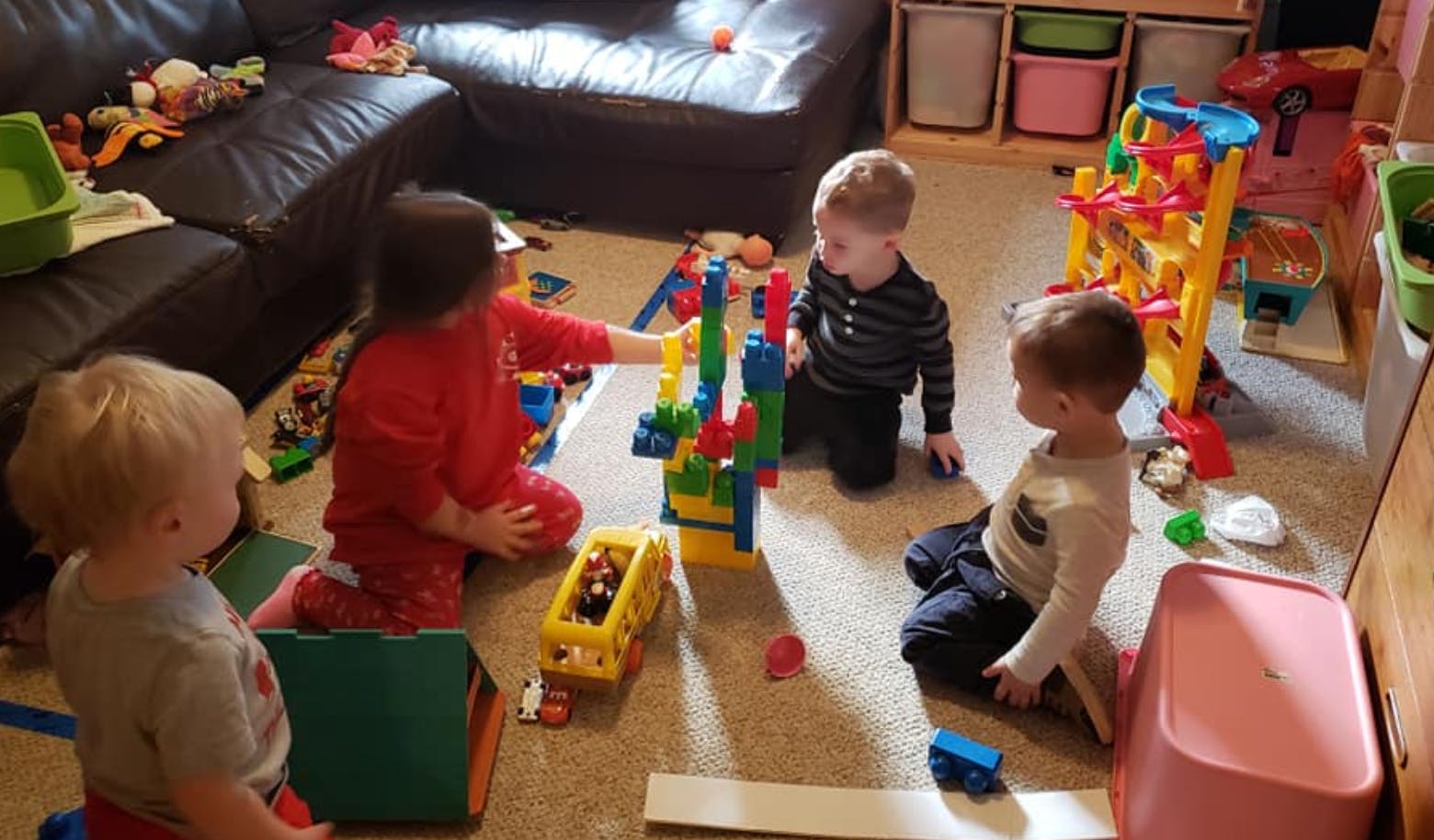 Four children playing with building blocks on the floor