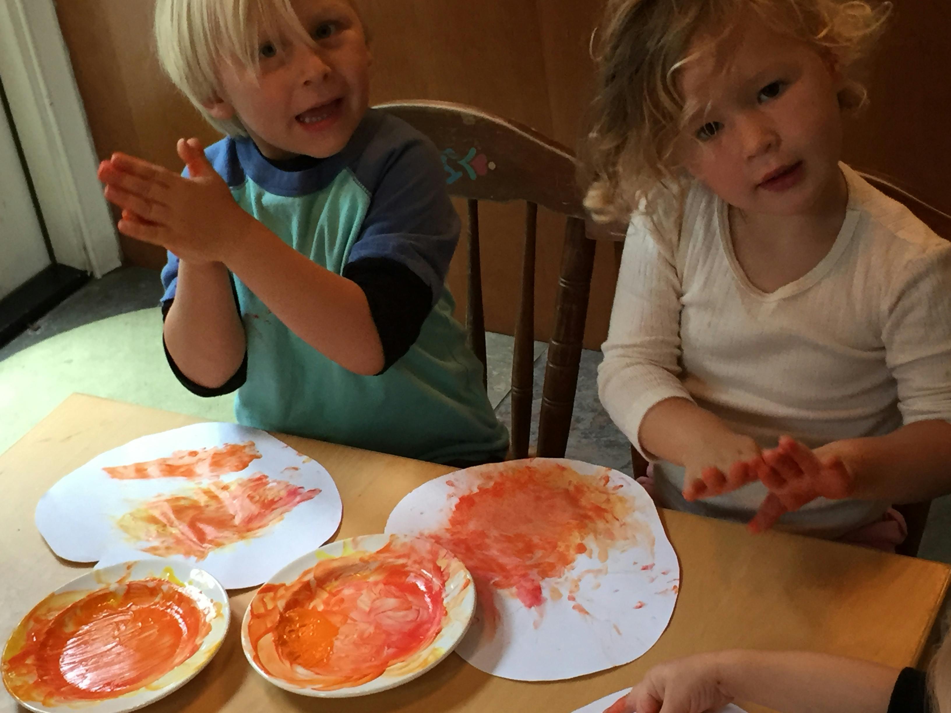 Two children finger painting at a table