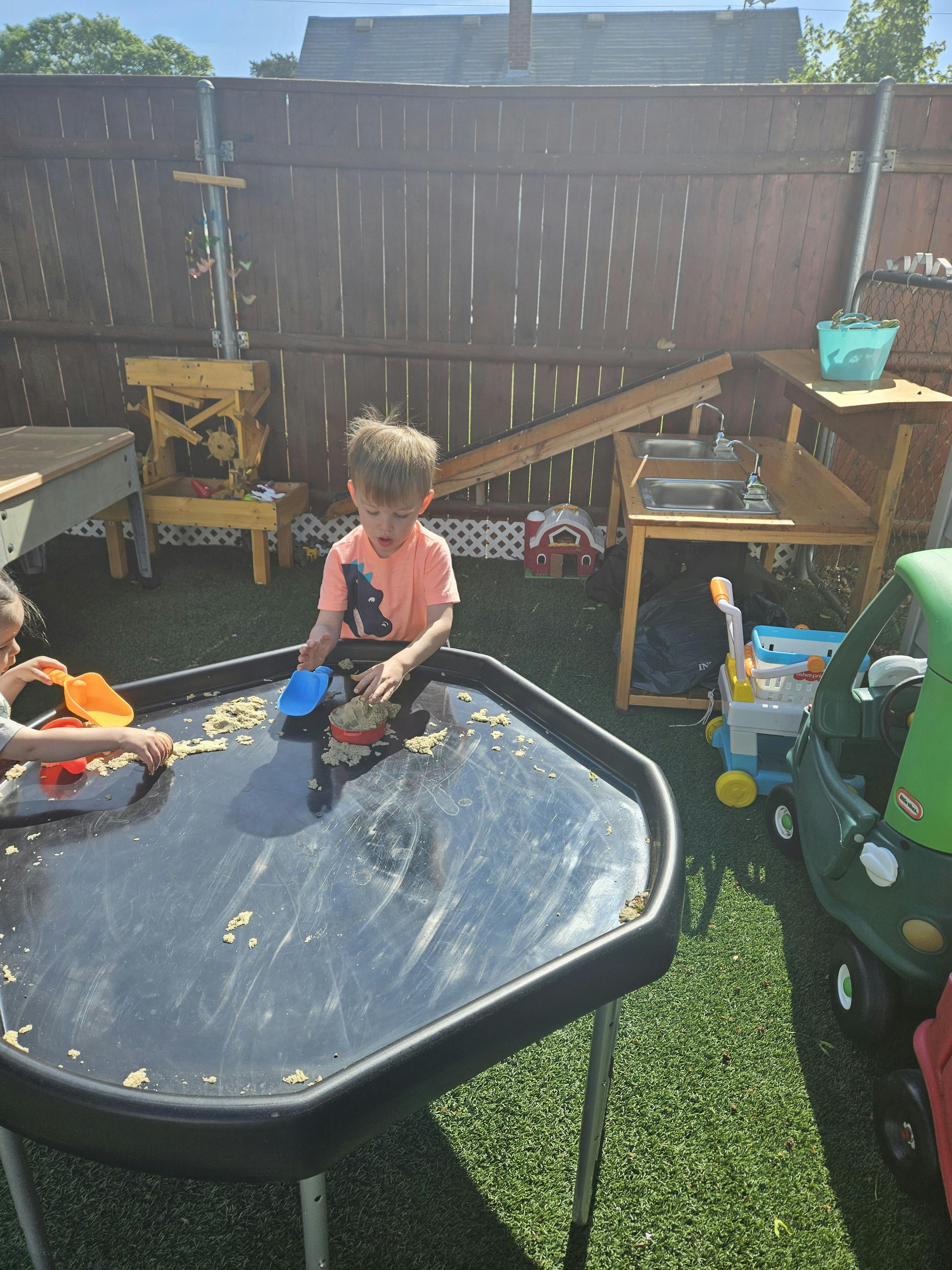 Child playing with sand and water at a sensory table outdoors