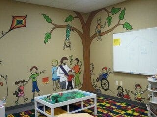 Children's room with wall murals of people and a tree
