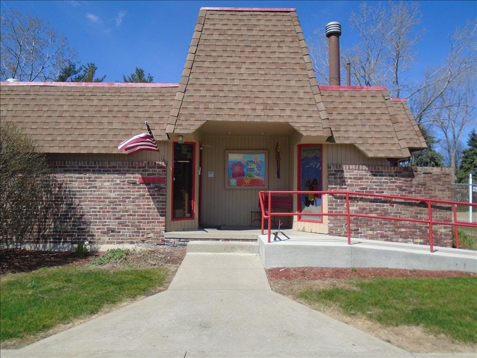 Brick building with a brown roof and red trim, with a flag hanging