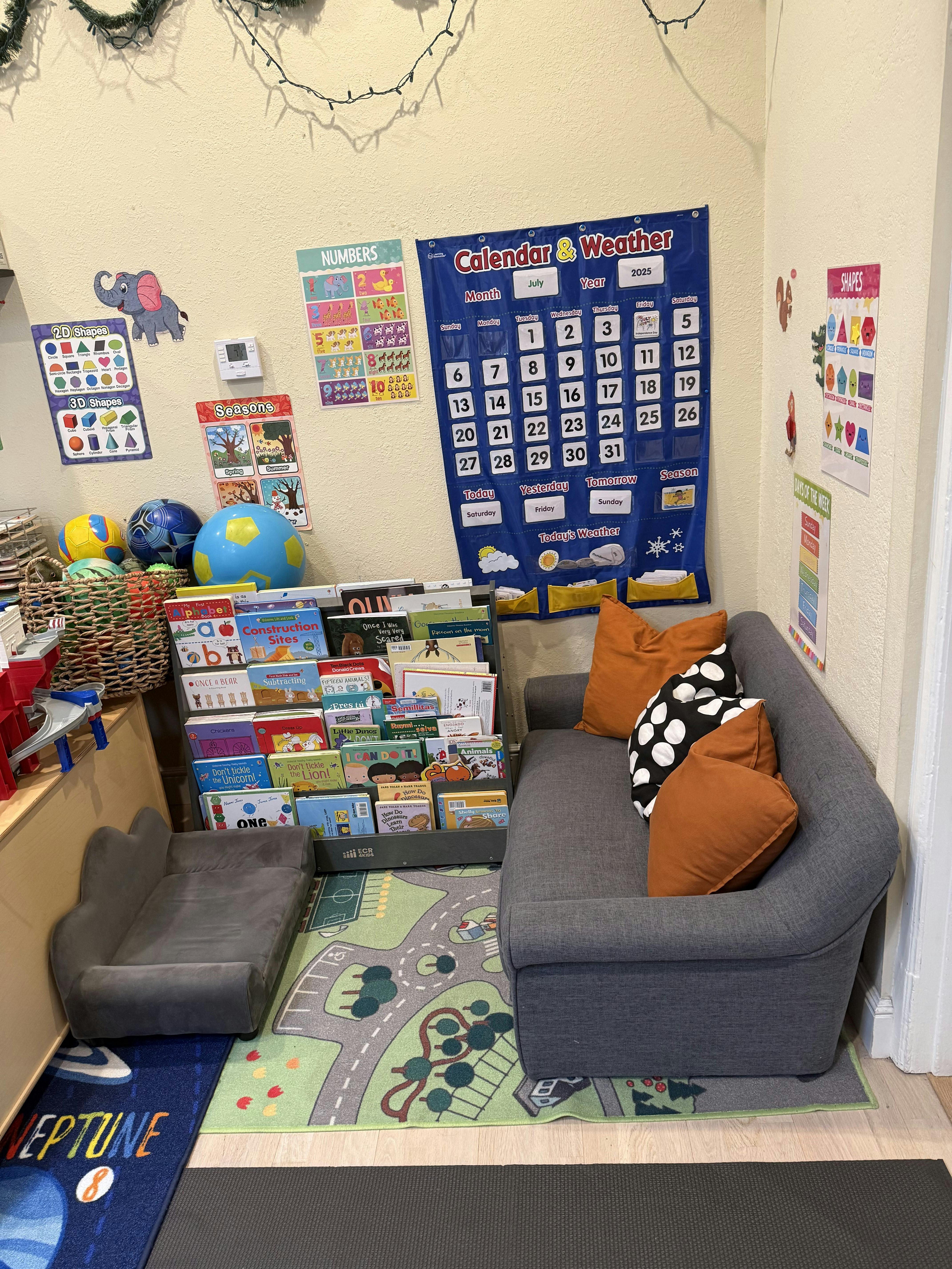Children's reading nook with a small sofa, book display, and wall calendar