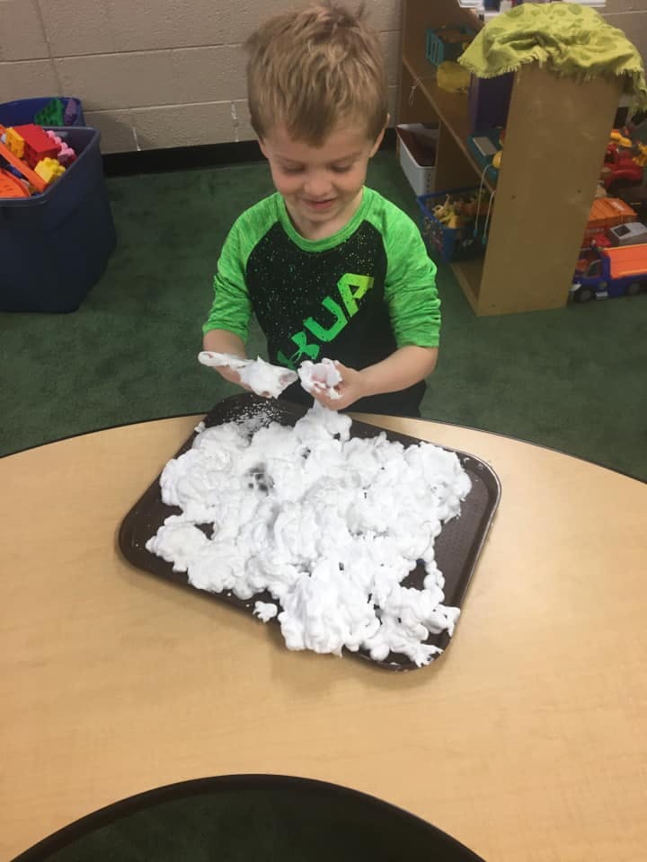 Child playing with shaving cream on a tray