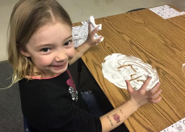 Child playing with shaving cream on a table