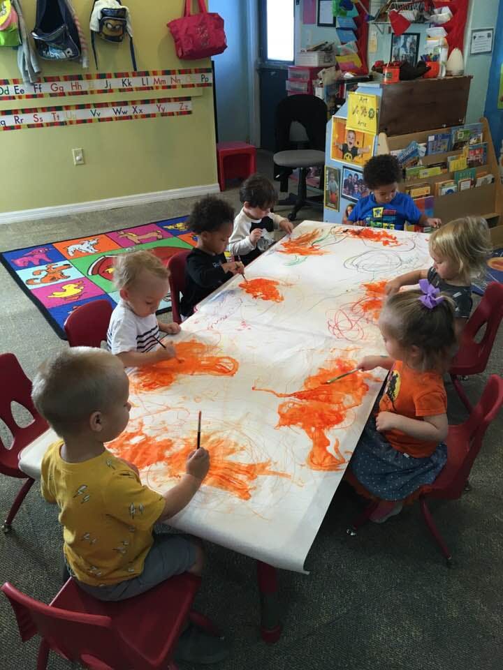Children painting at a table in a classroom