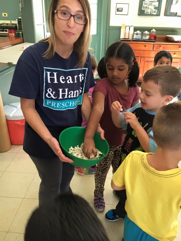 Person holding a bowl of popcorn for children to take some