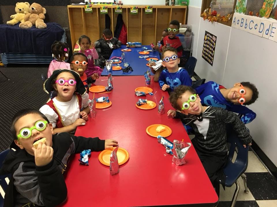 Children wearing novelty glasses sitting at a long table in a classroom