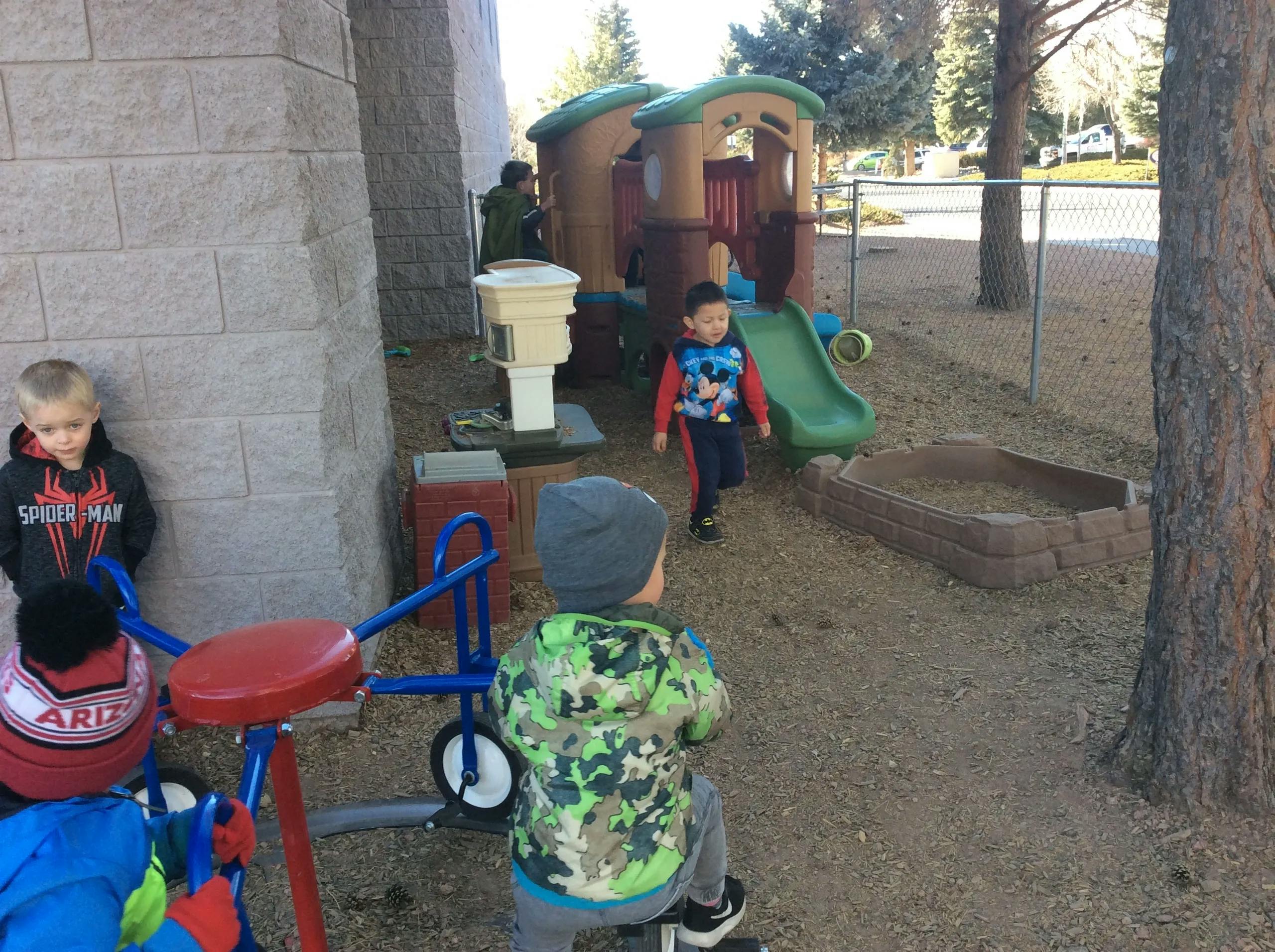 Children playing on a playground with a slide and playhouse