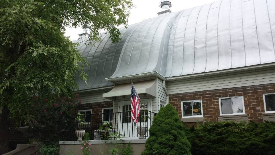 Building with a curved metal roof and an American flag hanging by the entrance