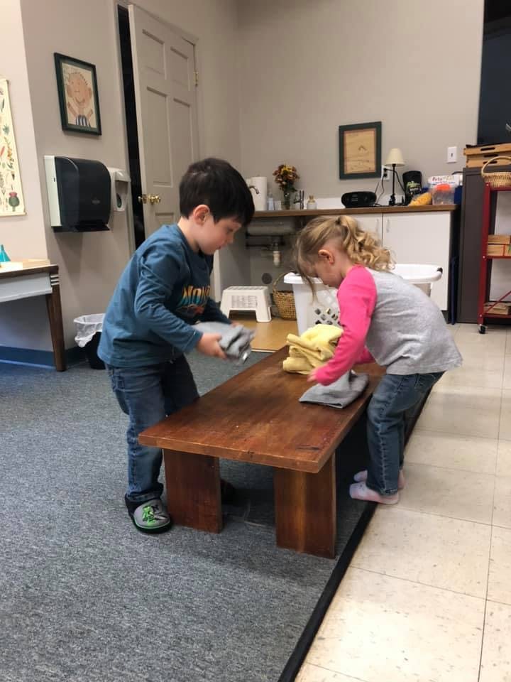 Two children folding towels on a wooden table