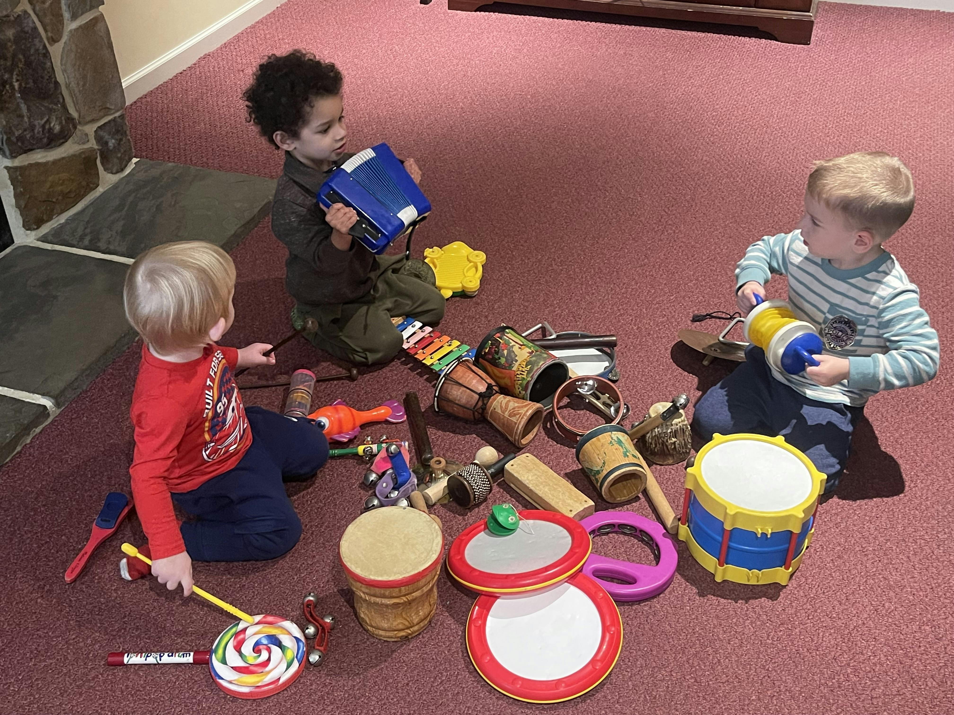 Three children playing with musical instruments on the floor