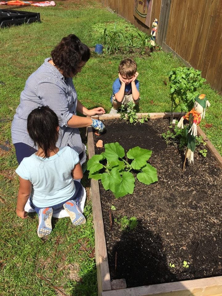Adult and two children gardening in a raised garden bed