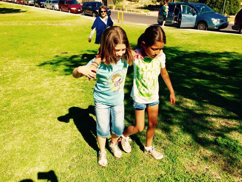 Two children walking together on grass