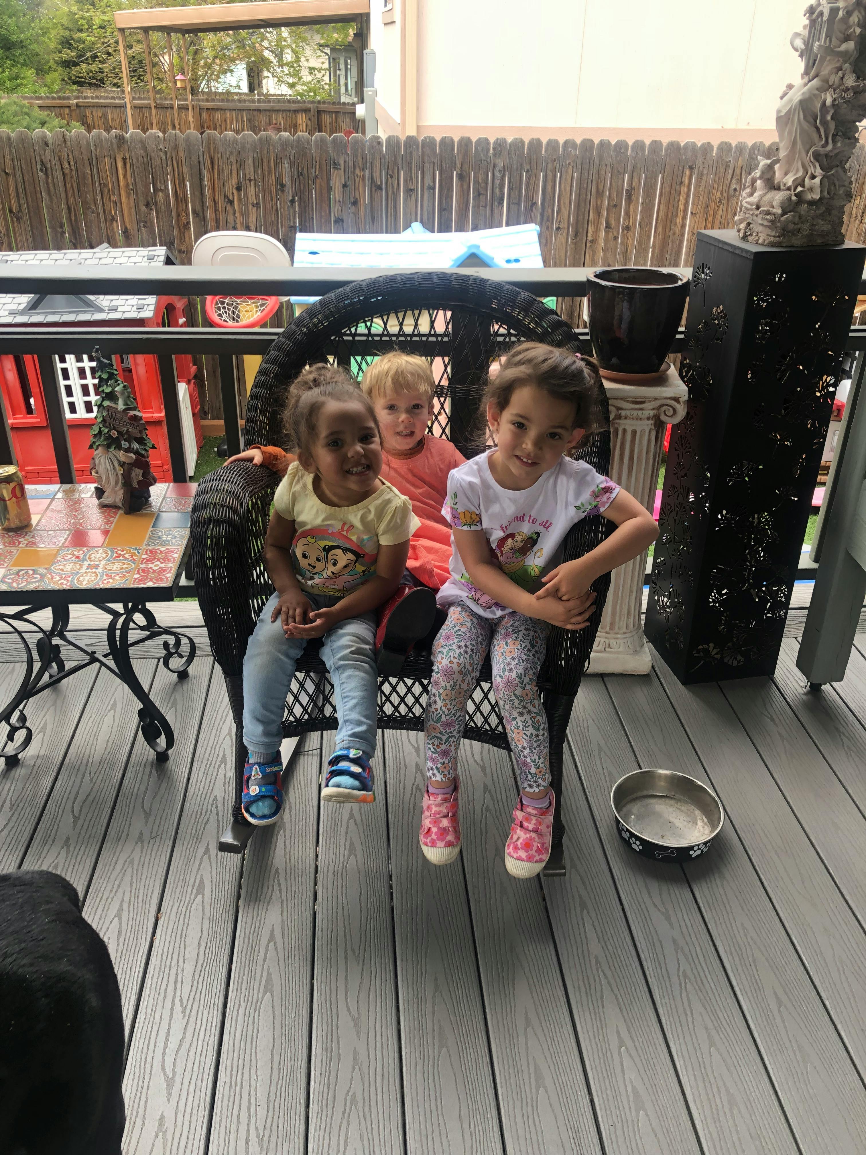 Three children sitting together on a wicker chair