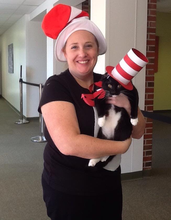 Person holding a cat, both wearing red and white striped hats