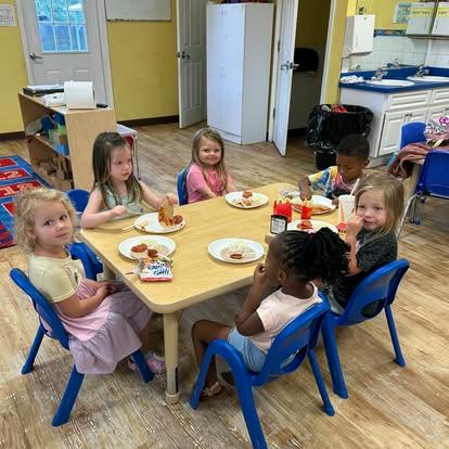 Group of children eating at a table in a classroom