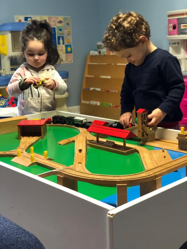 Two children playing with a toy train set on a table