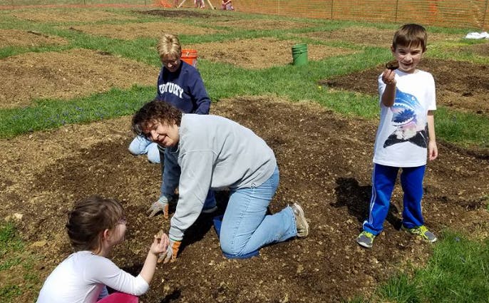 Adult and children planting in a garden