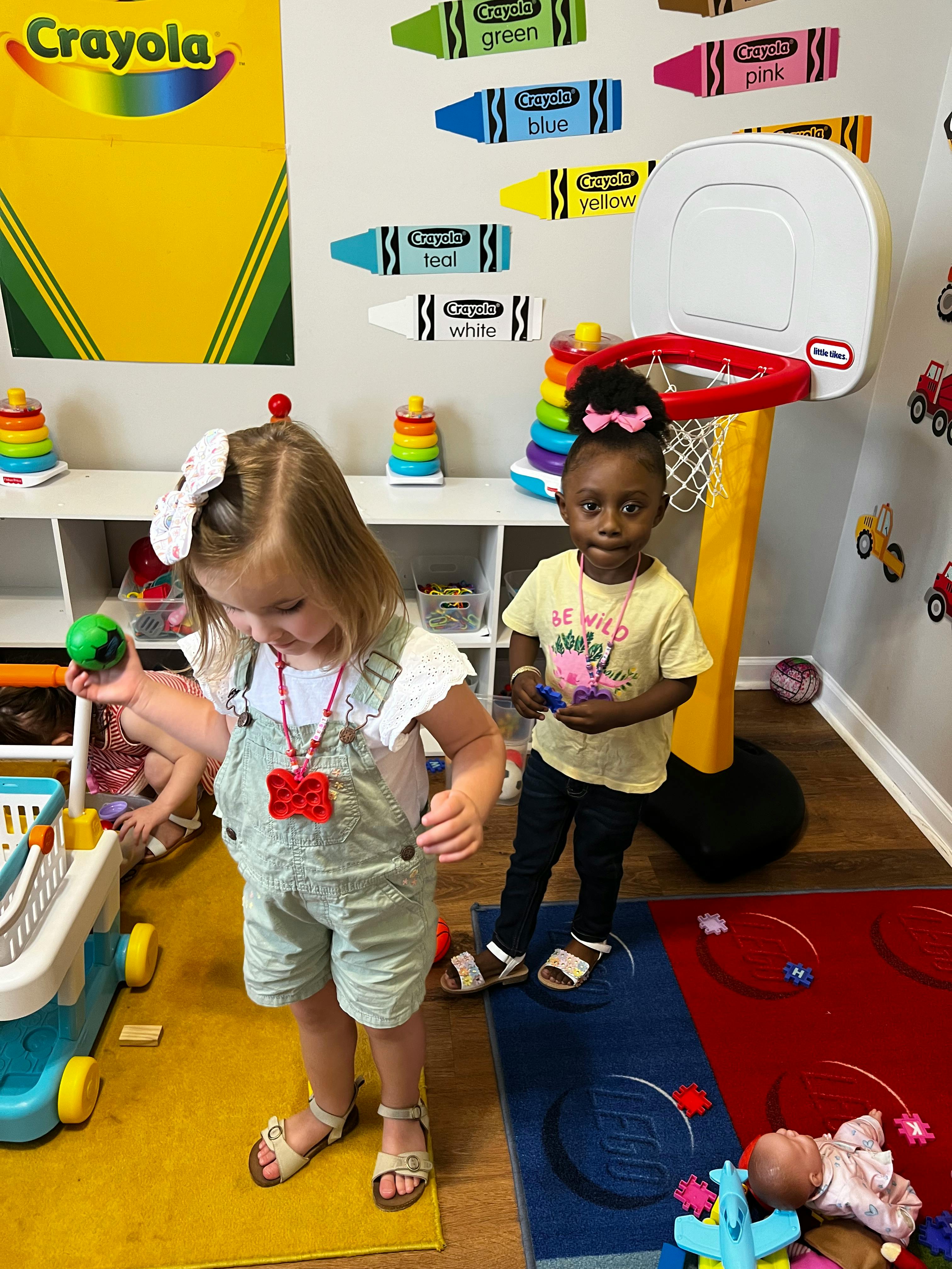 Two children playing in a room with a toy basketball hoop