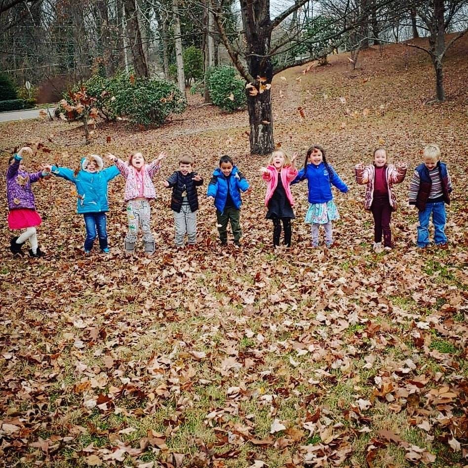 Group of children standing in a field of fallen leaves