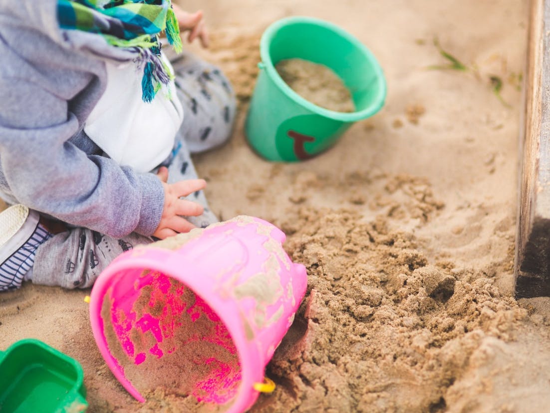 Child playing in a sandbox with buckets